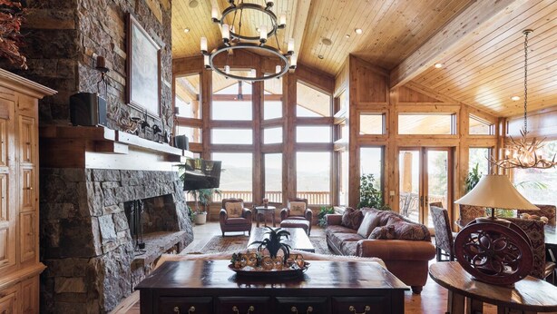 A spacious living area with a stone fireplace, wooden furniture, and large windows allowing natural light. - Deer Valley Cabin W/ Hot Tub | Theater (Park City)