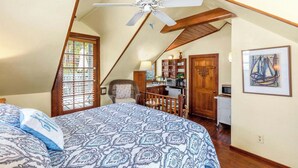 Een slaapkamer met een groot bed, een plafondventilator, een kitchenette en een eethoek.
