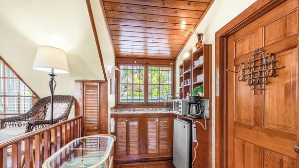Een houten interieur met een keuken, eethoek en een kleine koelkast.
