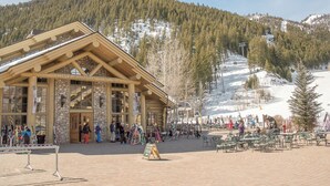 A lodge with a stone facade and large windows, surrounded by a snowy mountain landscape. - Christophe Condo 503 - Year-round Outdoor Pool and Hot Tub and Bald Mt. Views (Ketchum)