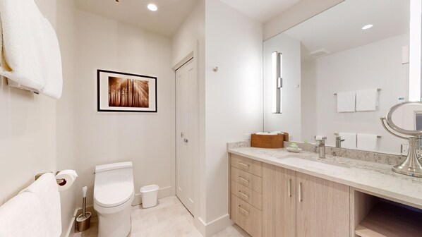 Un baño moderno con inodoro, lavabo y espejo.