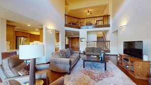 A spacious living area with a sofa, chairs, a coffee table, a TV, and a staircase leading to an upper level. - Summit Condo 2815 - Sweet Penthouse with Great Views (Elkhorn)