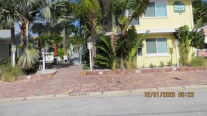 A two-story building with a sign reading "Palm Place" and a brick walkway leading to it. - Sabal Palm Unit 1 1 Beach Getaway (Clearwater Beach)