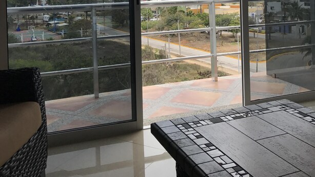 Un salon moderne doté d’une grande porte-fenêtre coulissante donnant sur un balcon. Le balcon offre une vue sur le paysage urbain, avec ses immeubles de grande hauteur et son ciel dégagé.