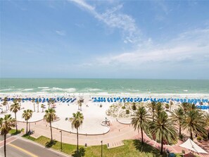A beach with blue umbrellas and palm trees.