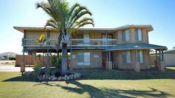 Stunning two-story home with a spacious balcony and covered porch, set amidst a beautifully manicured lawn.