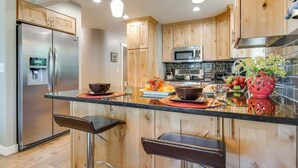 A modern kitchen with wooden cabinets, stainless steel appliances, and a central island with bar stools.
