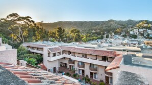 Bairro residencial com casas em socalcos, varandas e um relevo acidentado ao fundo.