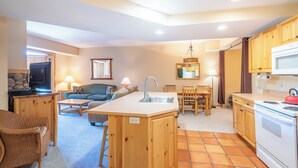 A compact kitchen with a central island, wooden cabinets, a microwave, and a stove. - Spacious condo that sleeps 4, steps from the lifts, free wifi & parking (Copper Mountain)