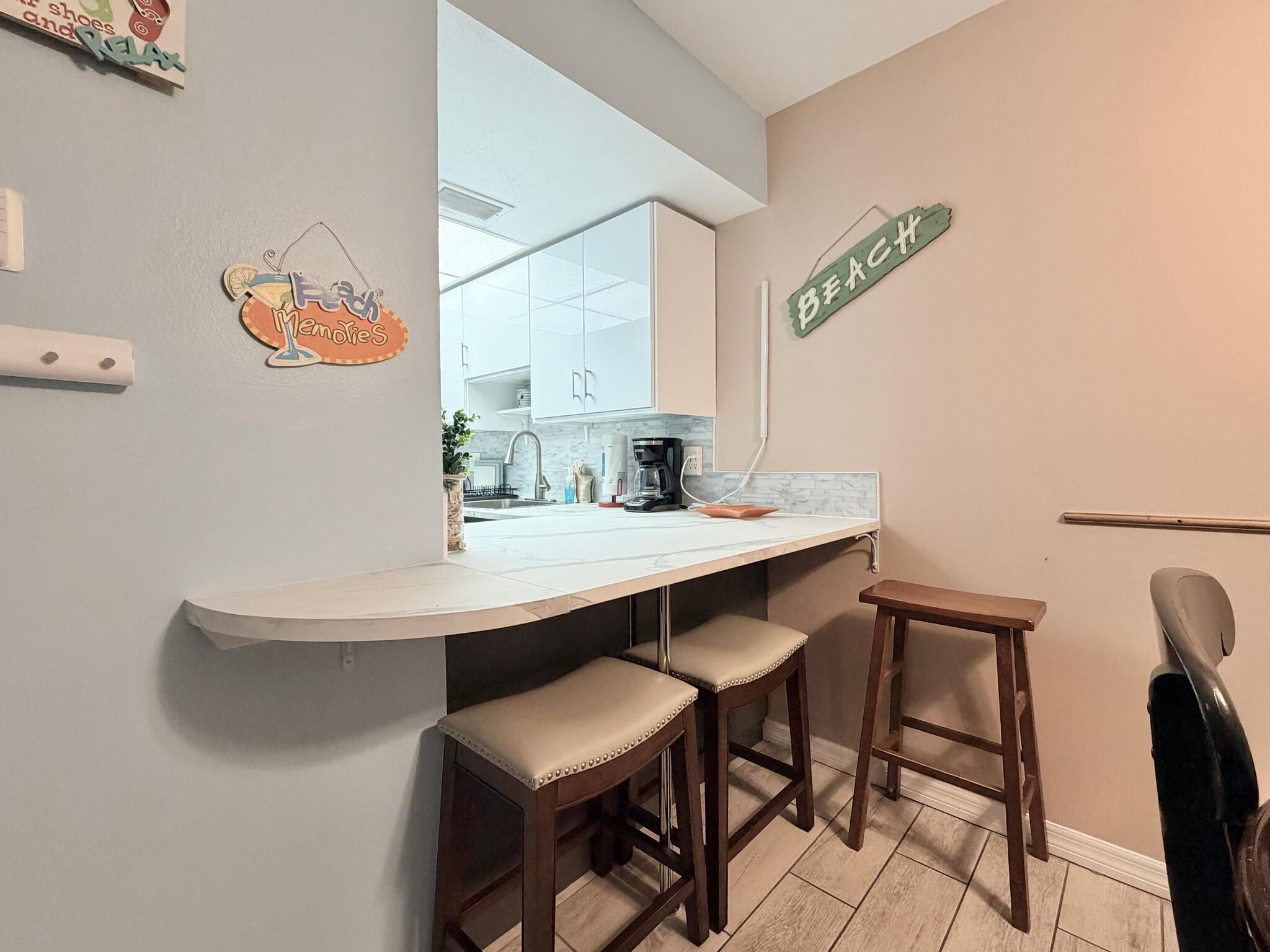 Una cocina con armarios blancos, una encimera y dos taburetes.