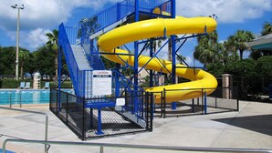 Parque acuático con un tobogán amarillo y escaleras azules.