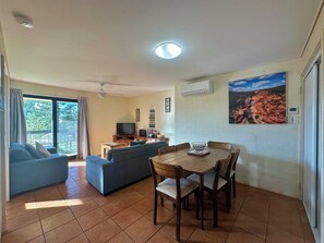 Relax in this stylish living area with a sofa, dining table, and flat-screen TV, offering a view of the outdoors.
