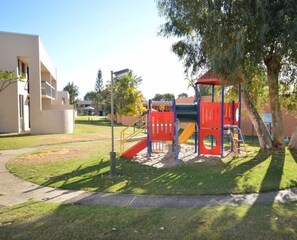 Children can play on the slide and climbing structure in the well-maintained lawn.