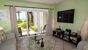 Ein Wohnzimmer mit Glastisch, Sofas, einem Fernseher und einem Bücherregal.