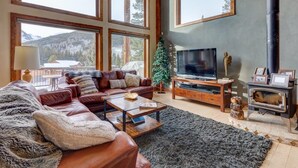 A cozy living room with a leather sofa, a coffee table, a fireplace, and a television.