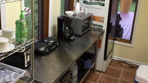 Une cuisine équipée d’une machine à café, d’un flacon de savon liquide et d’un carton de jus d’orange Tropicana Pure Premium.