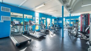 Un gimnasio con cintas de correr, elípticas y equipos de pesas.