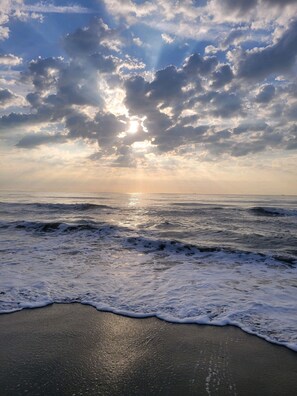 A beach with waves and a cloudy sky.