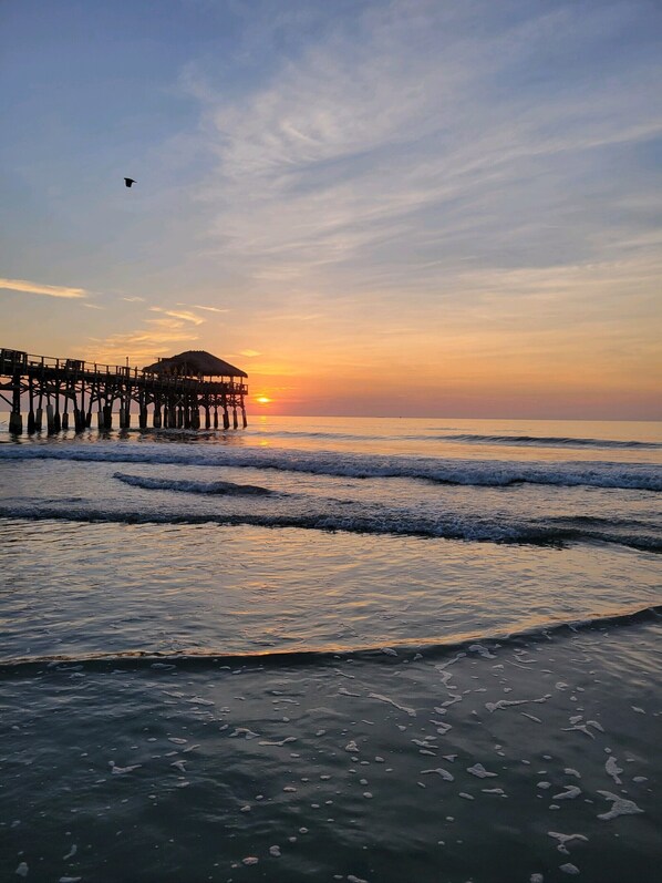 A pier extending into calm waters with a sunset in the background.