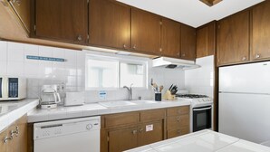 A modern kitchen with wooden cabinets, a dishwasher, a stove, and a microwave.