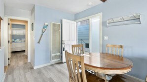 A dining area with a round wooden table and four chairs, a ceiling fan, and a wall-mounted shelf with decorative items.