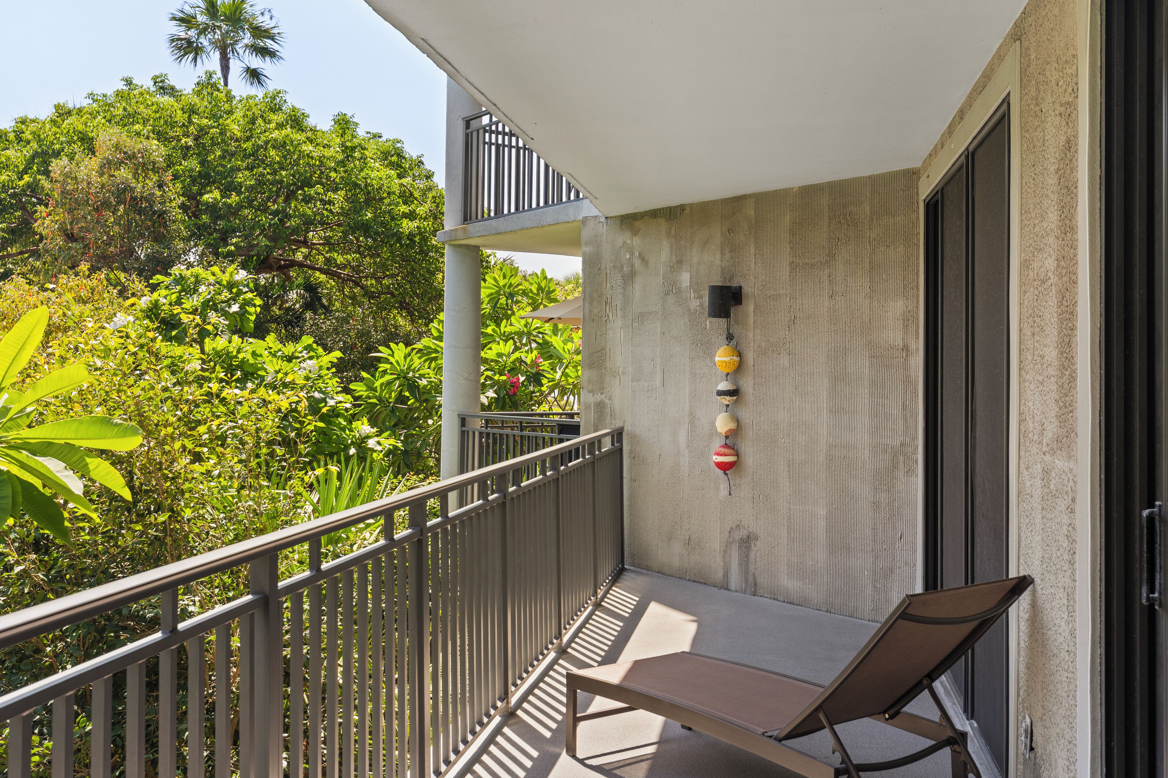 Un balcon doté d’une rambarde en métal, d’un banc et d’un mur en béton à la finition texturée.