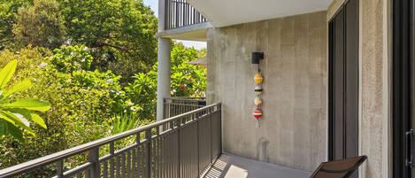 Un balcon doté d’une rambarde en métal, d’un banc et d’un mur en béton à la finition texturée.