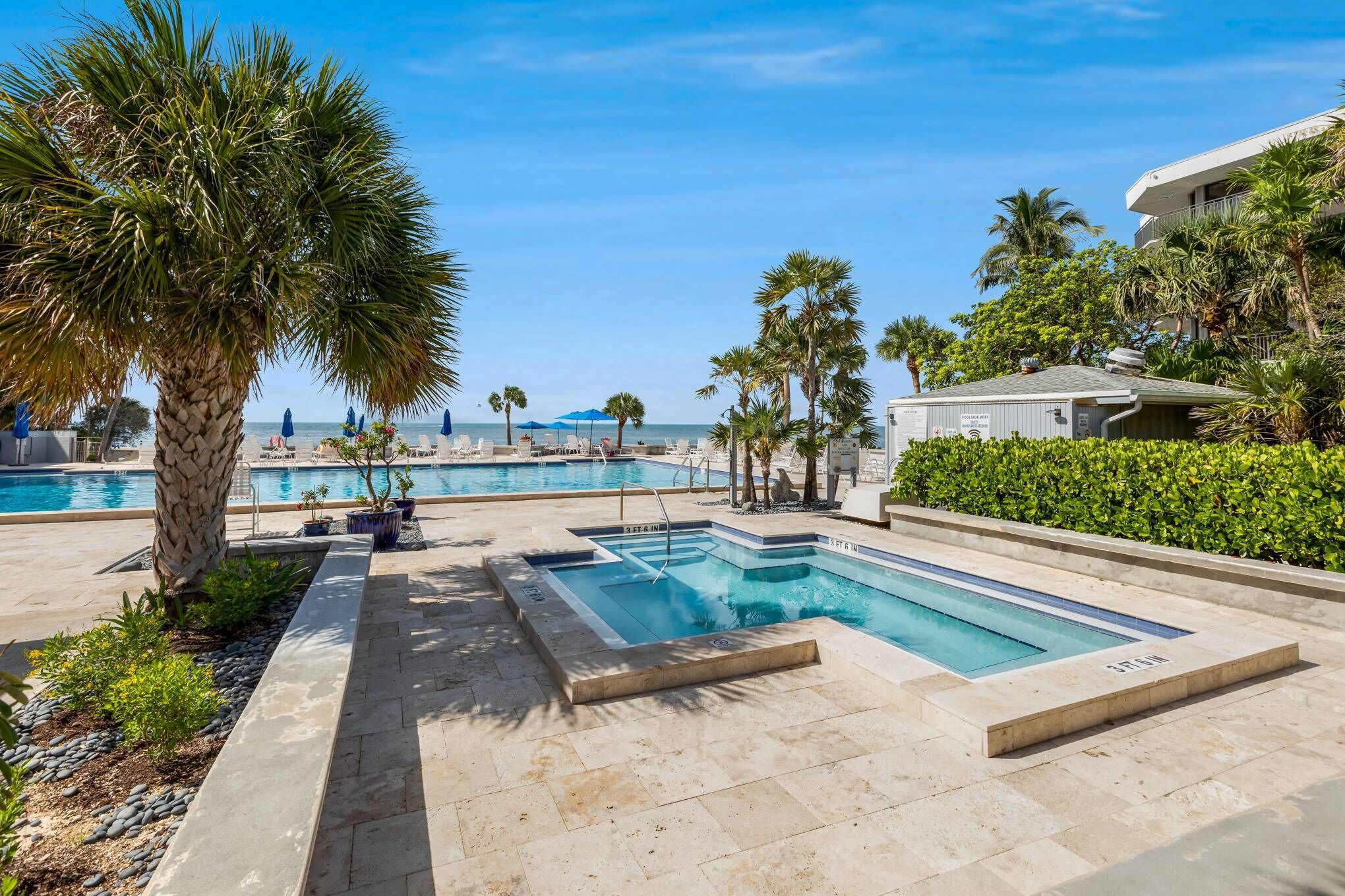 A pool area with multiple swimming pools, palm trees, and a building in the background.