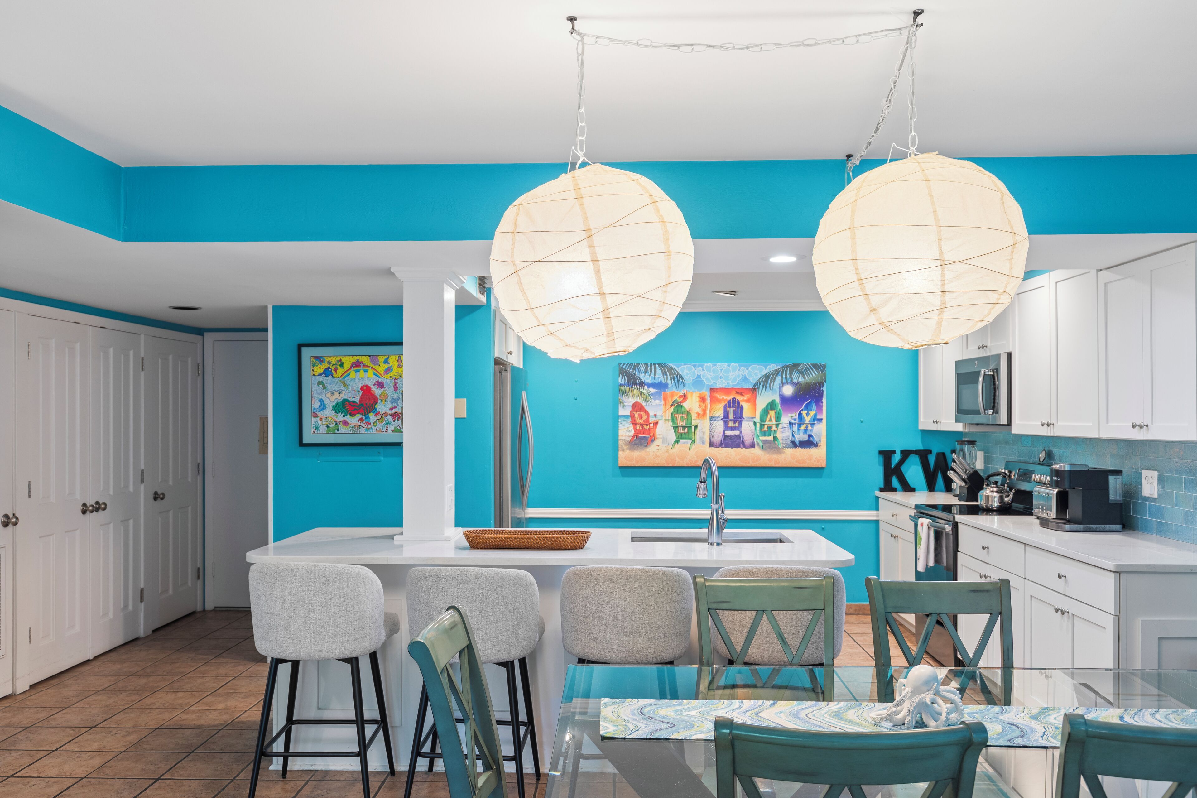 A modern kitchen with a blue accent wall, white cabinets, and a central island with bar stools.