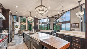 Una cocina amplia con una isla grande, muebles oscuros y múltiples lámparas colgantes.