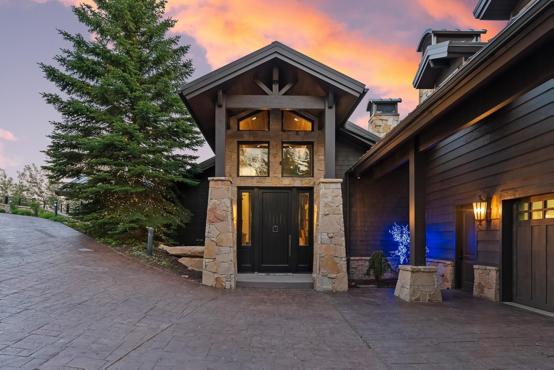 A modern house with a stone facade, a dark front door, and a garage.