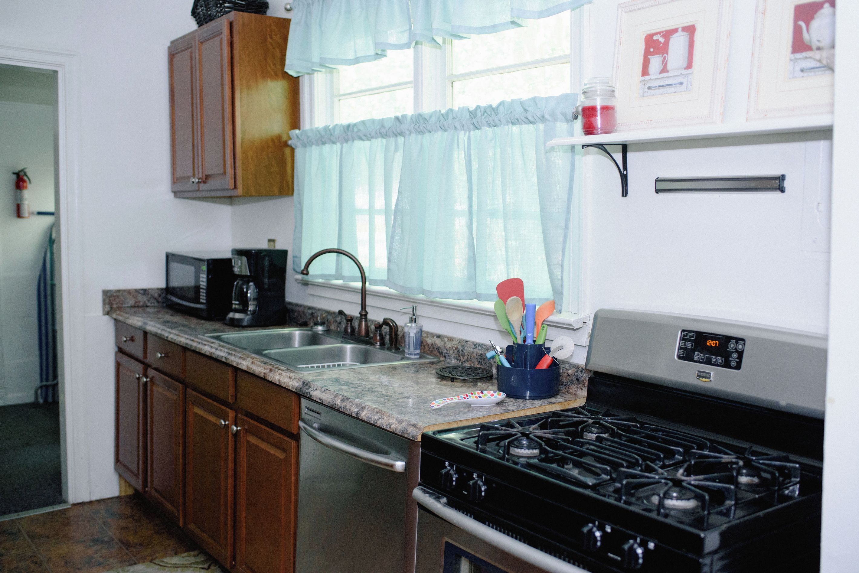 Una cocina con estufa, fregadero y armarios.
