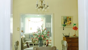 A dining area with a table set for two, a chandelier, and a vase with flowers. - The Original Crafter's Cottage Convenient to Savannah (Bloomingdale)