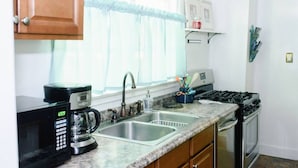 A kitchen with a coffee maker, sink, stove, and cabinets. - The Original Crafter's Cottage Convenient to Savannah (Bloomingdale)