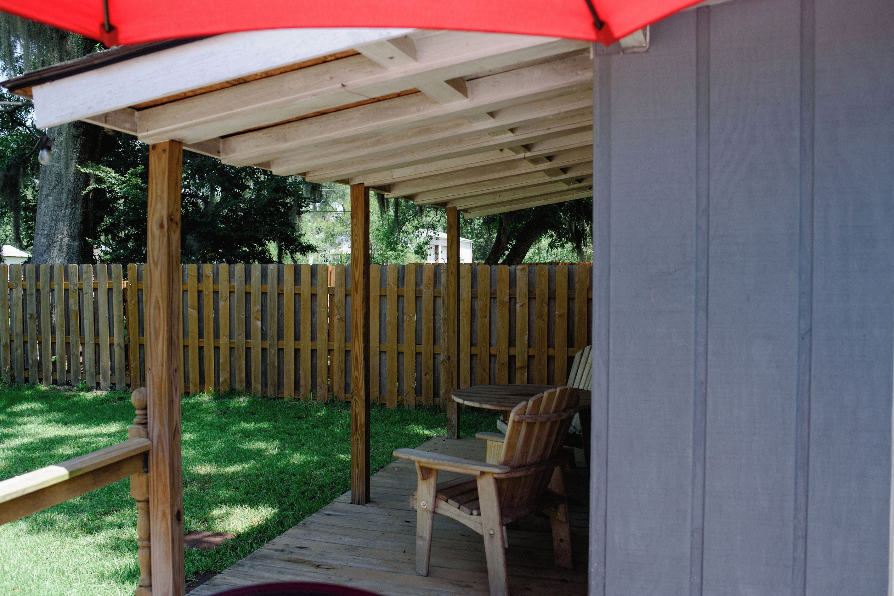 Un patio techado con terraza de madera, una mesa y dos sillas.