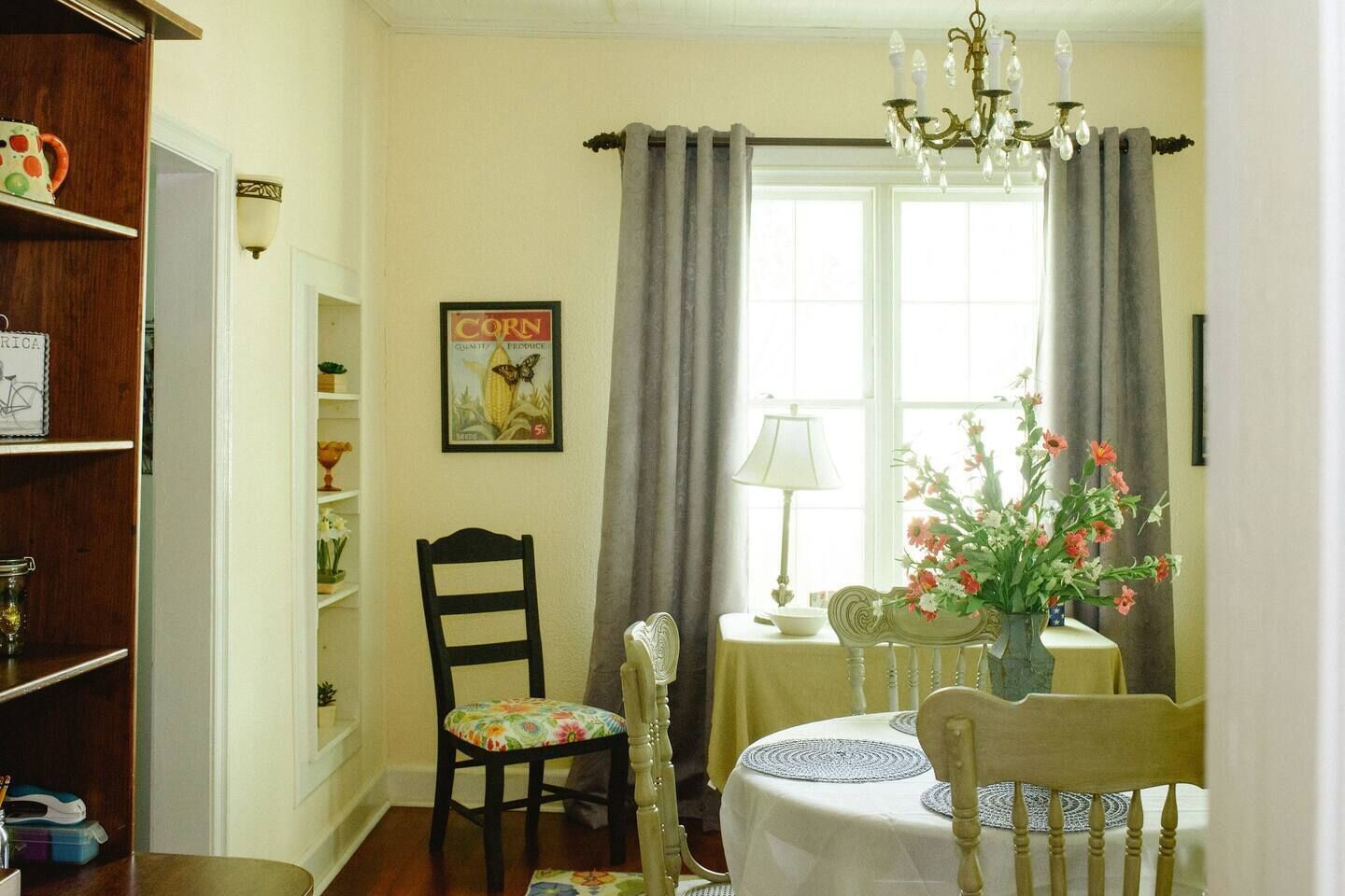 Un comedor con una mesa preparada para dos, un centro de mesa floral y un candelabro antiguo.