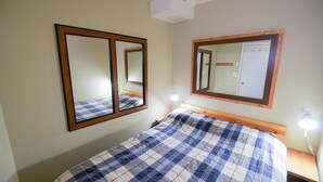 Un dormitorio con cama, dos espejos en la pared y lámparas de noche.