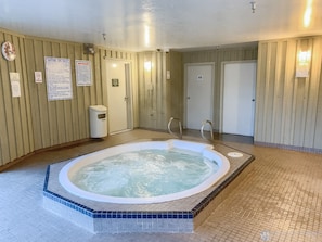Un área de spa con hidromasaje, paredes de madera y suelo de baldosas.