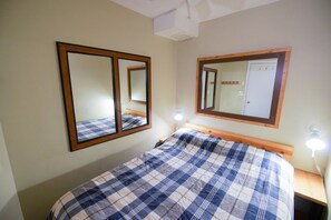 Un dormitorio con cama, dos espejos en la pared y lámparas de noche.