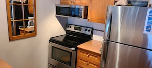 Una cocina con estufa, microondas y refrigerador.