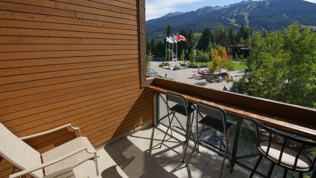 Un balcón con vistas a montañas, una pared de madera y mobiliario para exteriores.