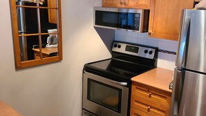 Una cocina con un refrigerador de acero inoxidable, un microondas, una estufa y armarios de madera.