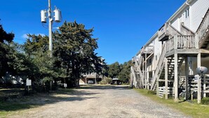 Un chemin de gravier menant à un bâtiment doté d’un escalier en bois et d’une antenne parabolique.