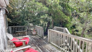 Une terrasse en bois dotée d’une rambarde, entourée d’arbres.