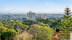 Un edificio alto con varios pisos, rodeado de abundante vegetación y zonas residenciales.