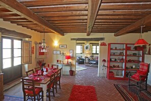 Un vaste espace de vie comprenant une table à manger pour quatre personnes, un canapé rouge et une bibliothèque rouge.