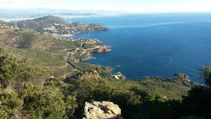 A coastal landscape with a winding road, rocky cliffs, and a view of the sea. - F9 Large bright apartment, 3 rooms, beach at 50m, swimming pool and sea view  (Théoule Sur Mer)