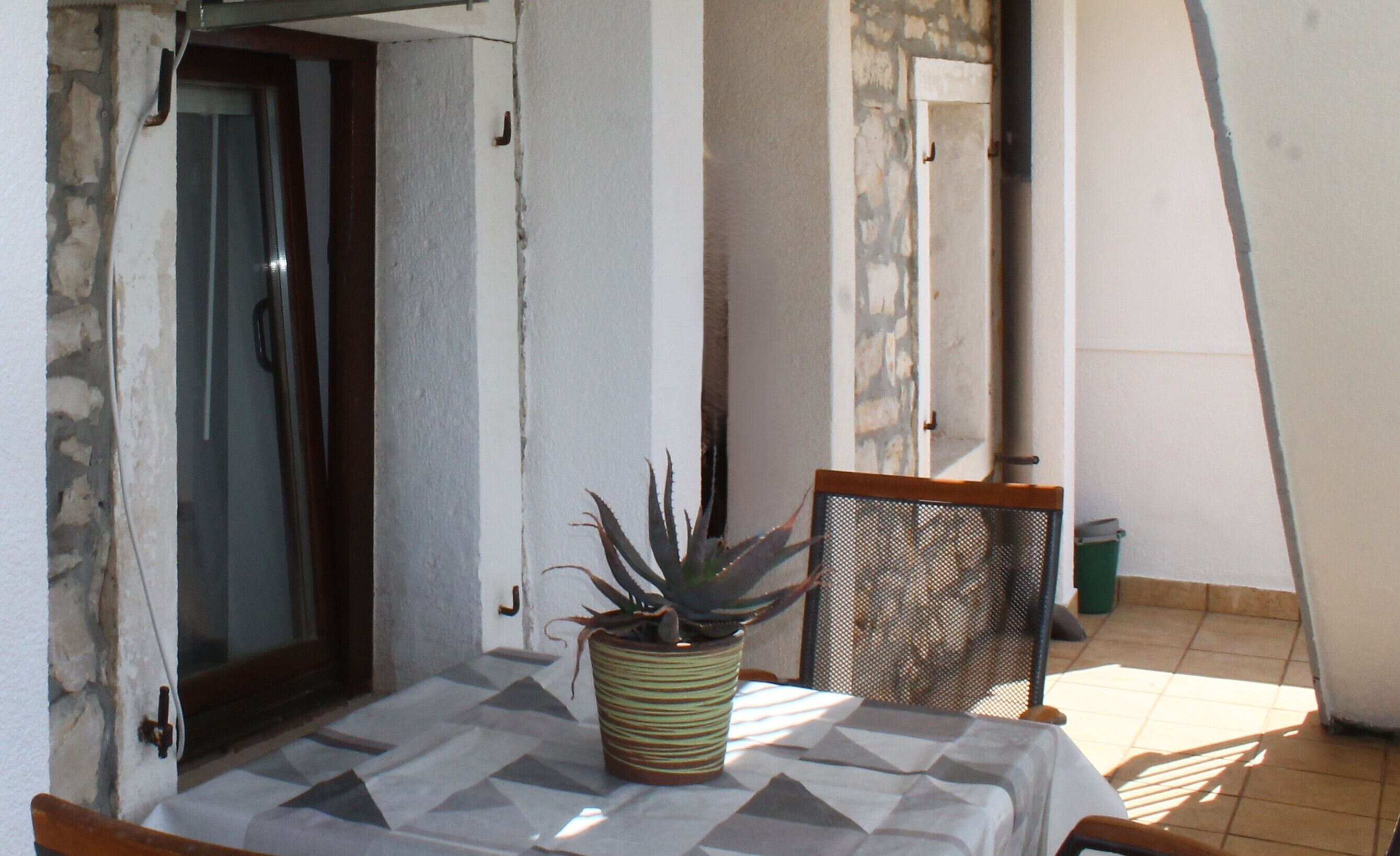 A small patio area with a table, a chair, and a potted plant.