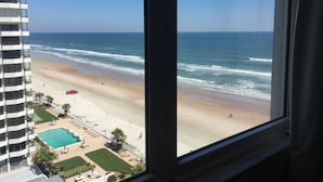 A view of a beach from a window overlooking a pool area and a building. - Spacious, updated 1 bed/1 bath condo with gorgeous ocean views (Daytona Beach)