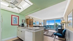 Een ruime woonkamer met een kookeiland, een eetgedeelte met uitzicht en een balkon met tuinmeubilair.